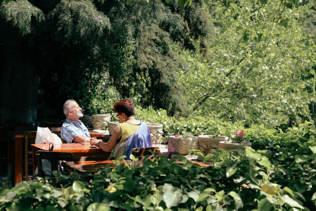 Persone sedute intorno a un tavolo in giardino durante un momento di convivialità