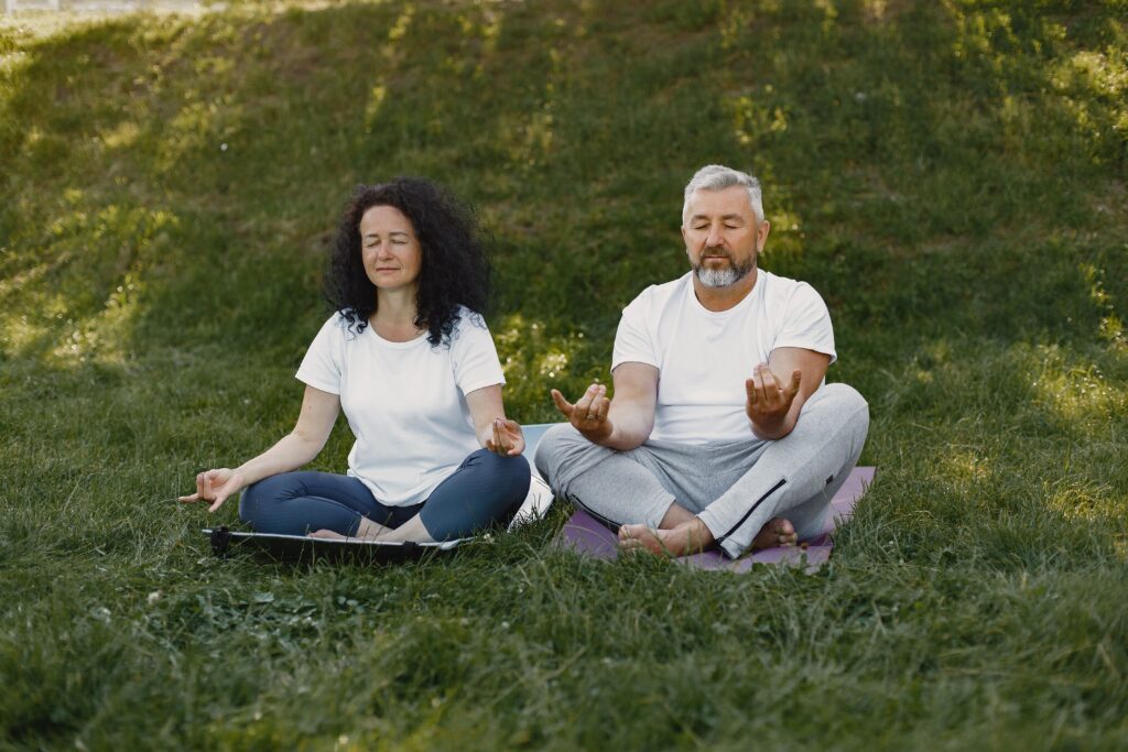 Due persone sedute sull'erba durante una sessione di meditazione all'aperto